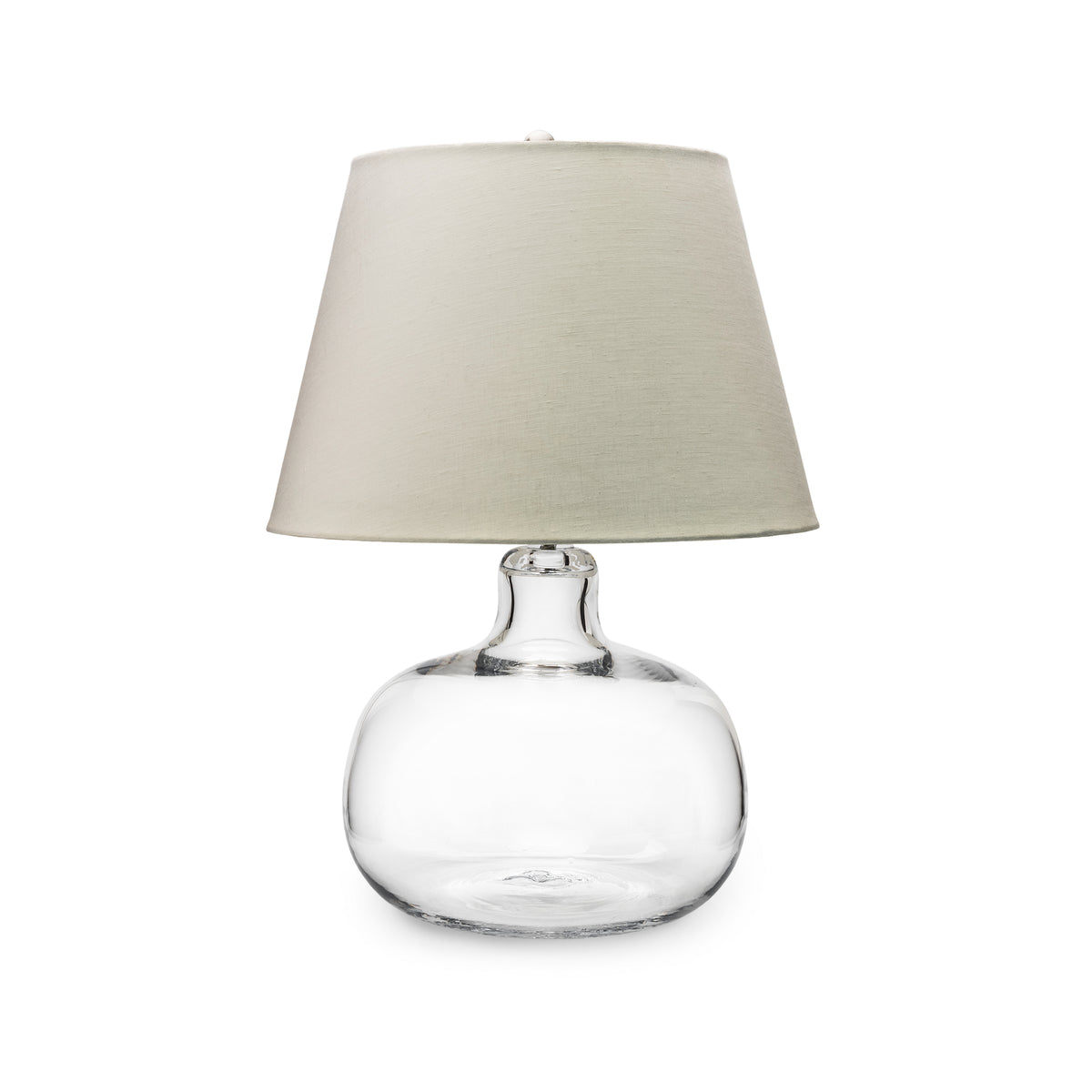 Clear glass rounded base lamp with cream-colored linen cylindrical shade.