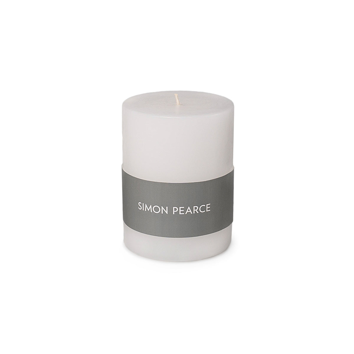 White cylindrical pillar candle with gray band label reading "SIMON PEARCE" and single wick.