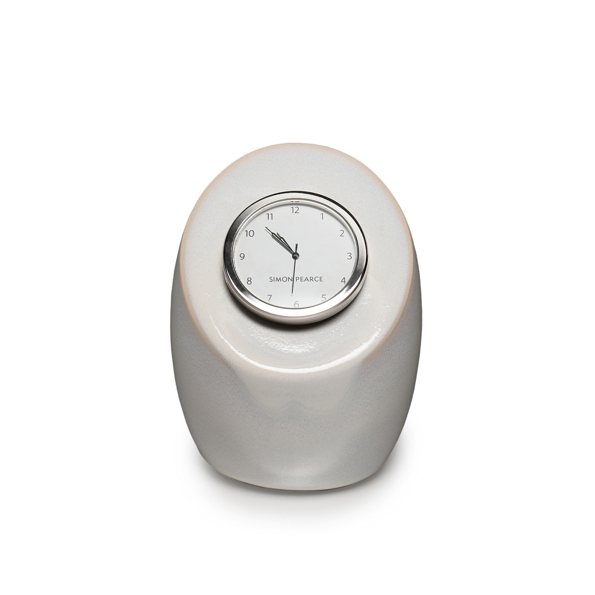 Cream pottery clock with rounded oval base and circular dial marked with Simon Pearce branding.