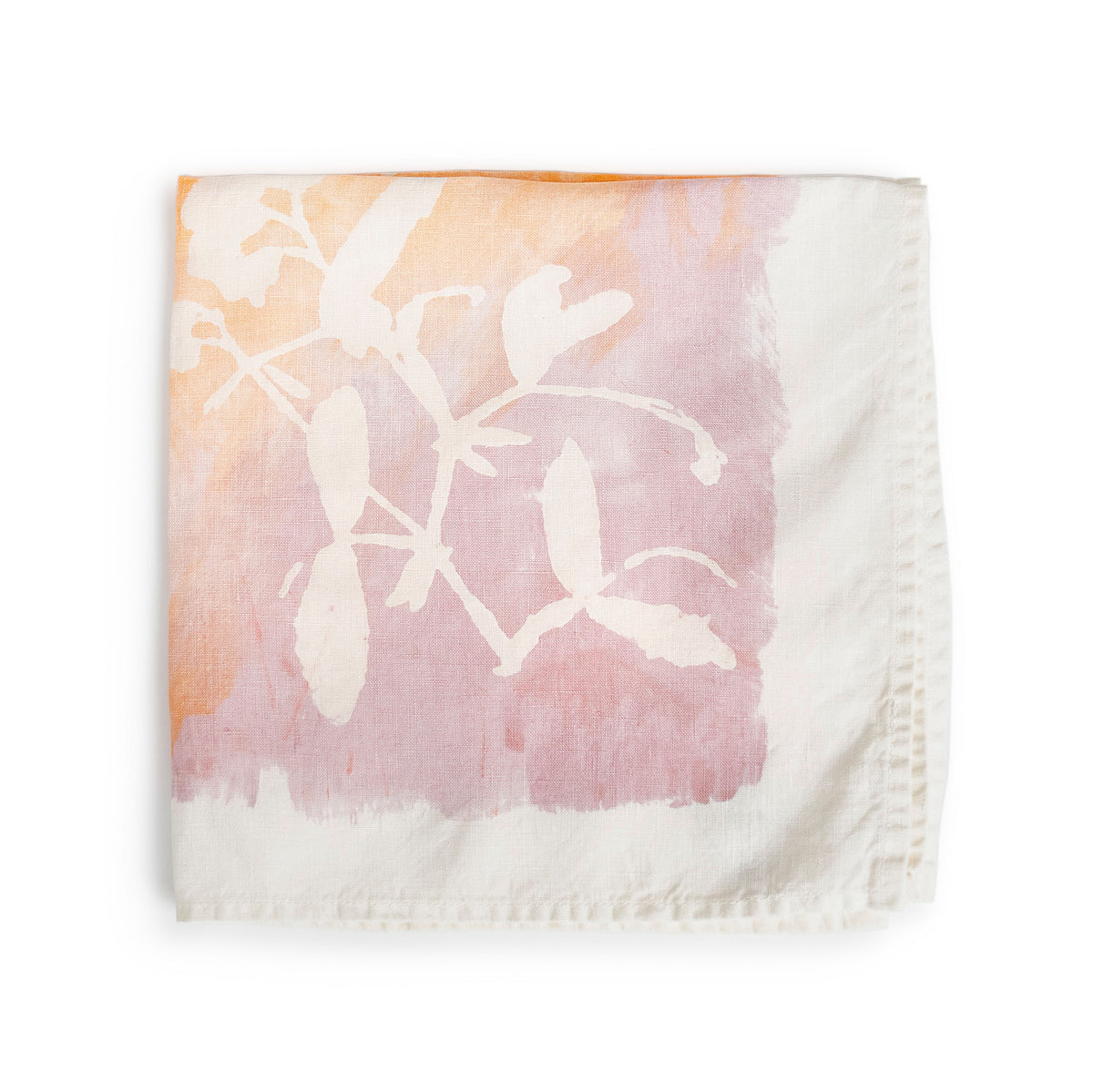 Apricot linen napkin with white botanical leaf print fading from peachy-orange to mauve tones.