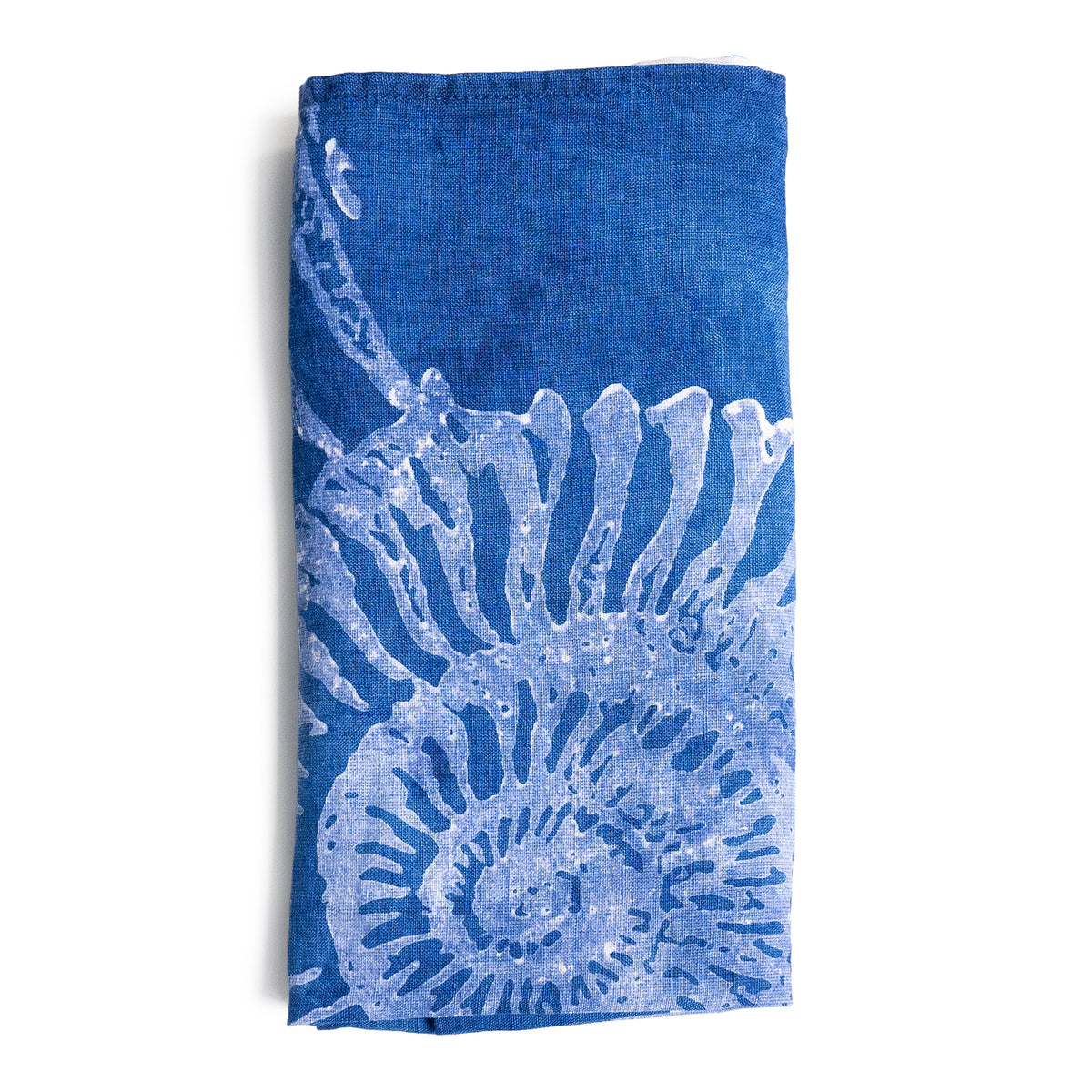 Indigo linen napkin with light blue shell and spiral motif printed on lower half.