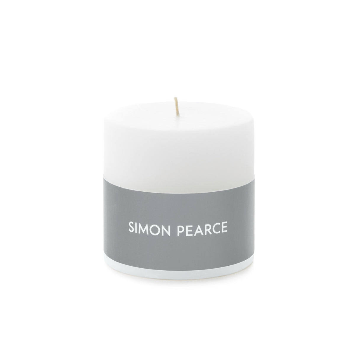 White cylindrical pillar candle with gray band labeled "SIMON PEARCE" and tan wick.