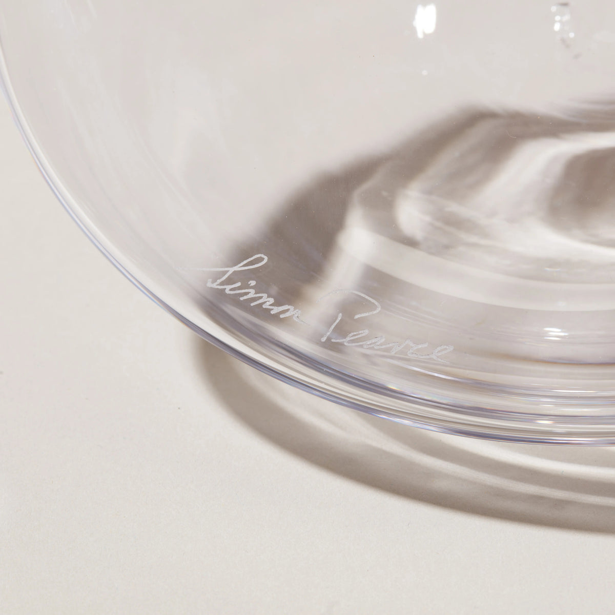 Clear glass wine decanter with etched signature on the bowl and curved spout detail.