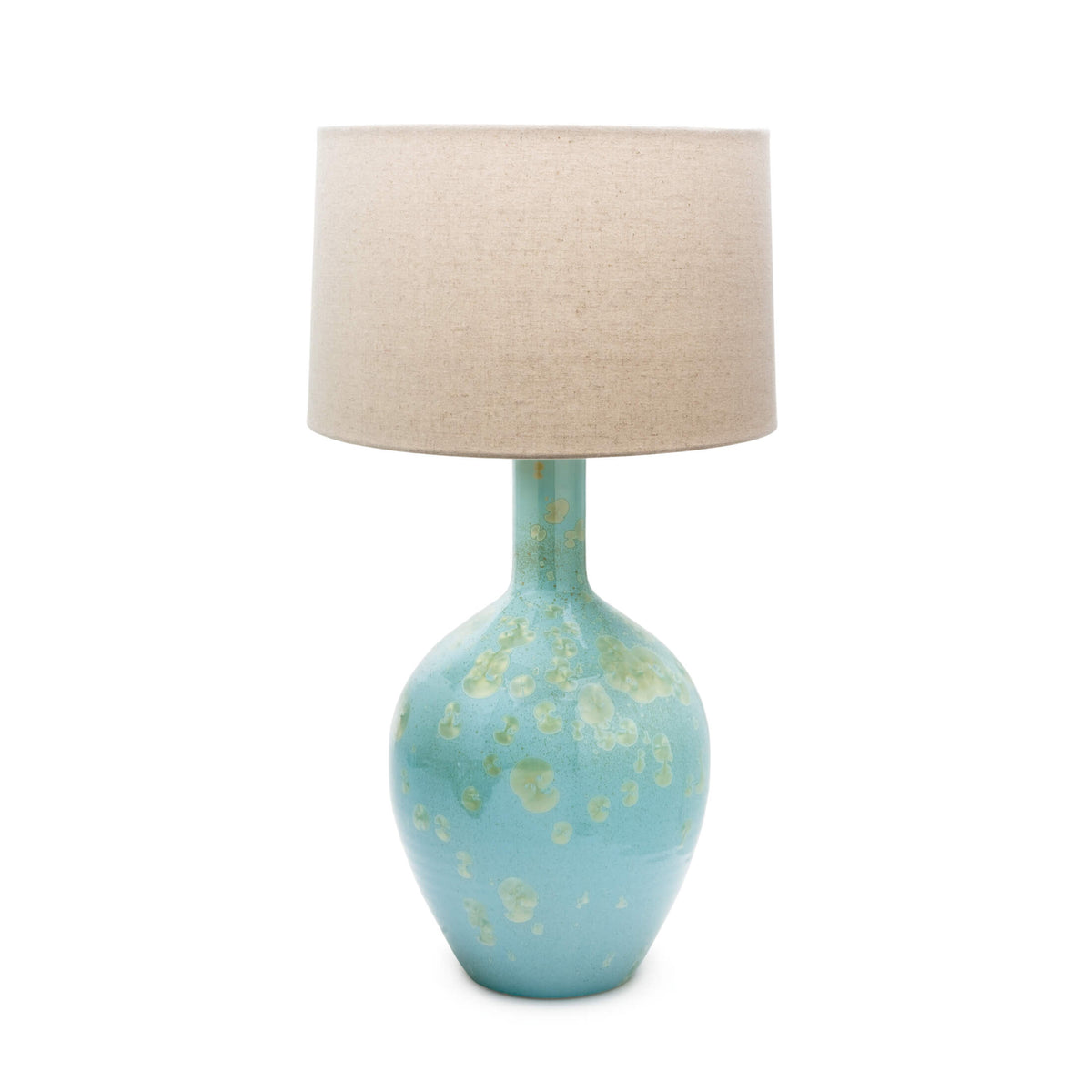 Table lamp with turquoise ceramic base featuring metallic accents and cream linen drum shade.