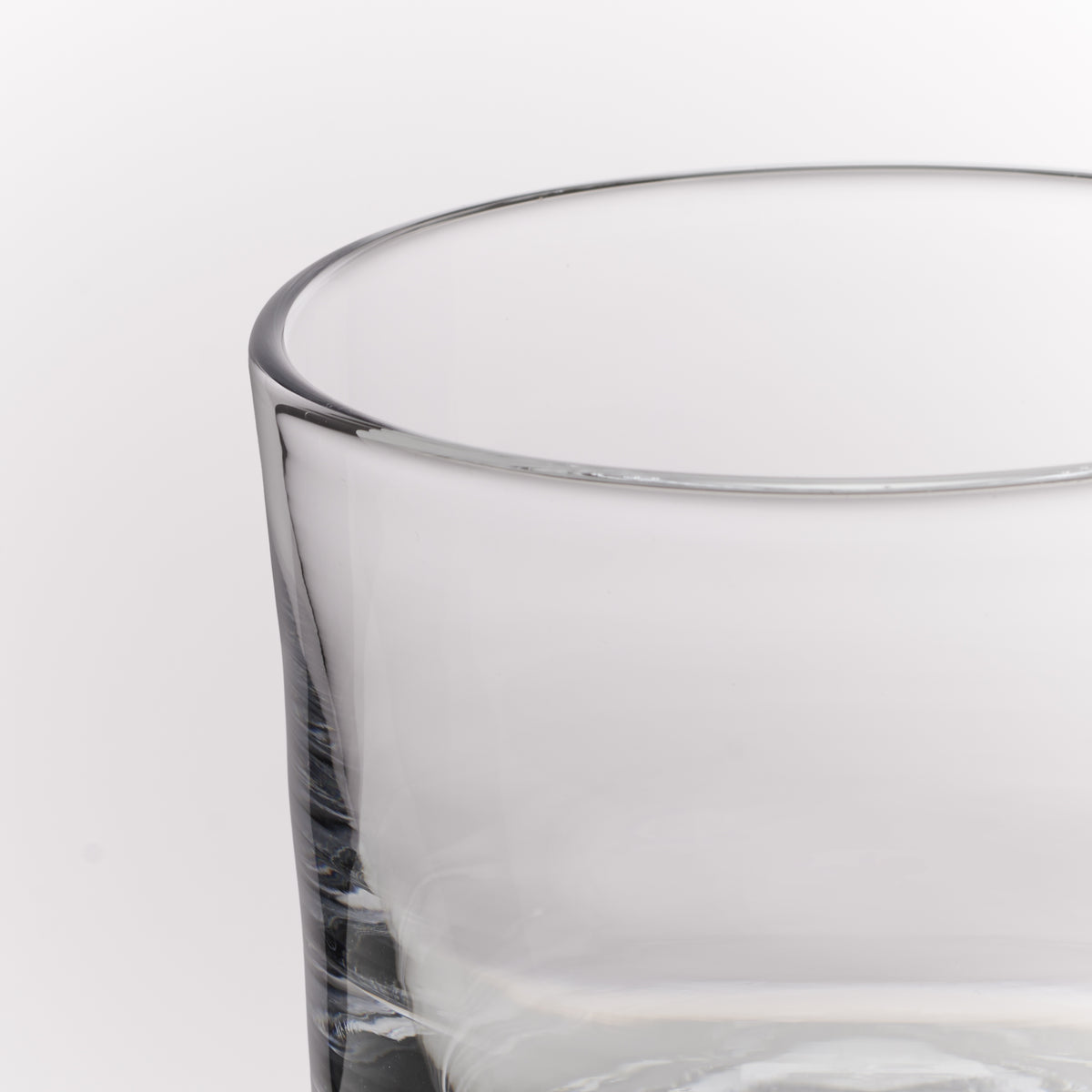 Close-up of a clear glass tumbler with a thick base on a white background.