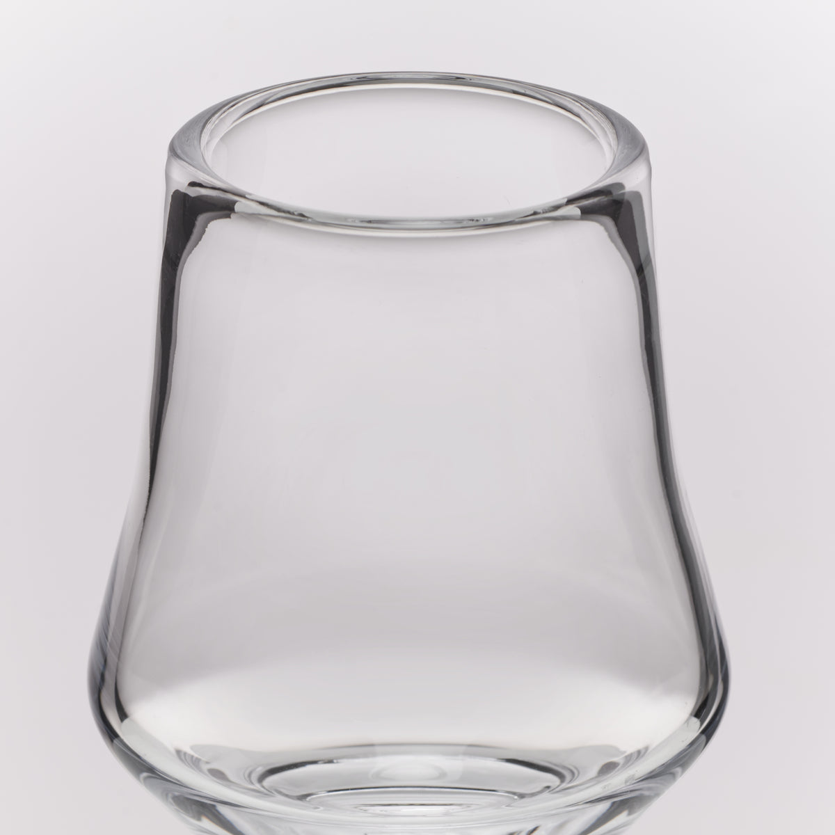 Clear glass tumbler with a wide rim and tapered base, photographed on a light gray studio background.