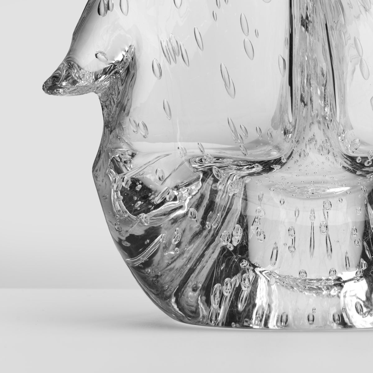 Clear glass vessel with twisted design and textured bubble pattern, filled with dark liquid and water droplets.