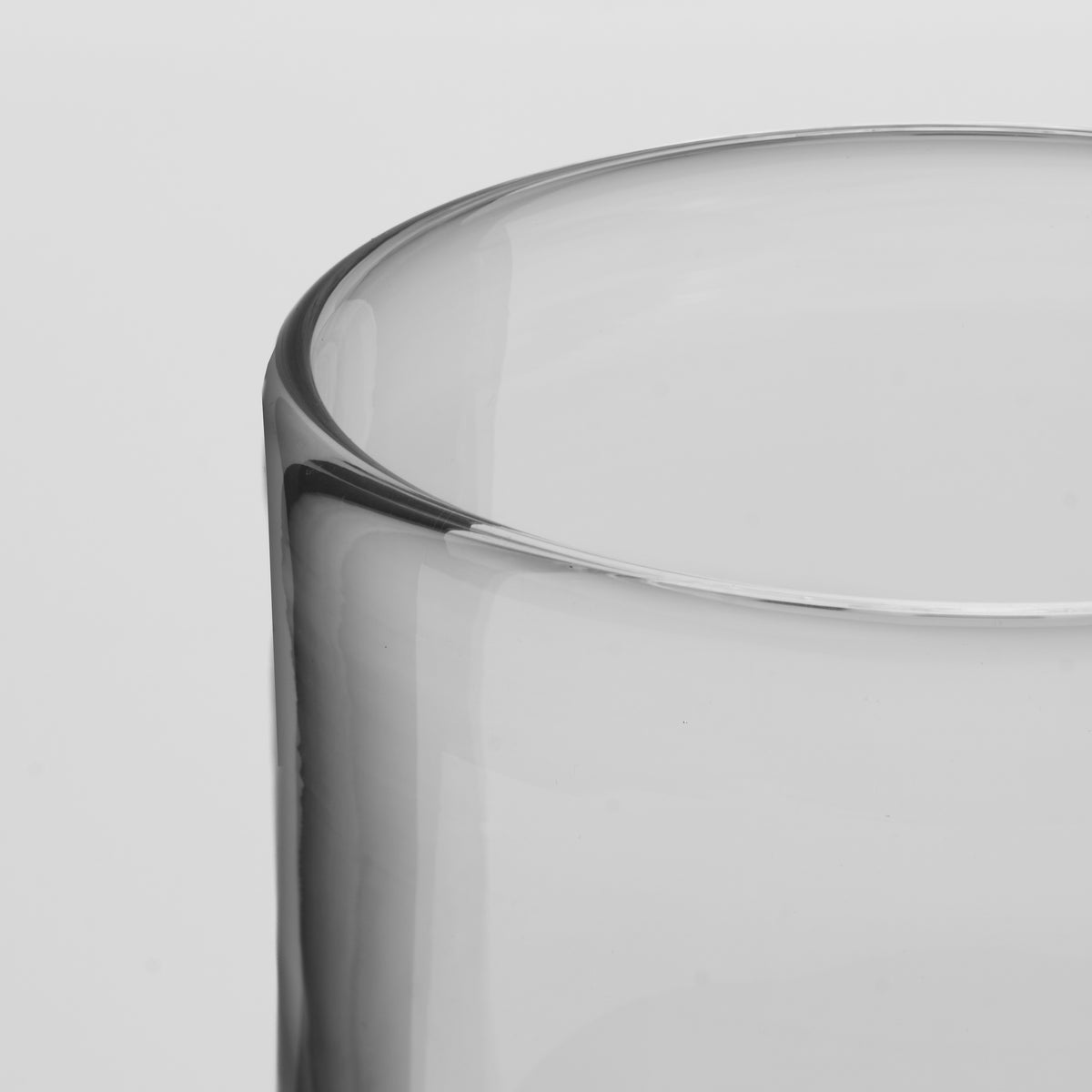 Close-up of a clear glass tumbler showing the rim and side profile against a light gray background.