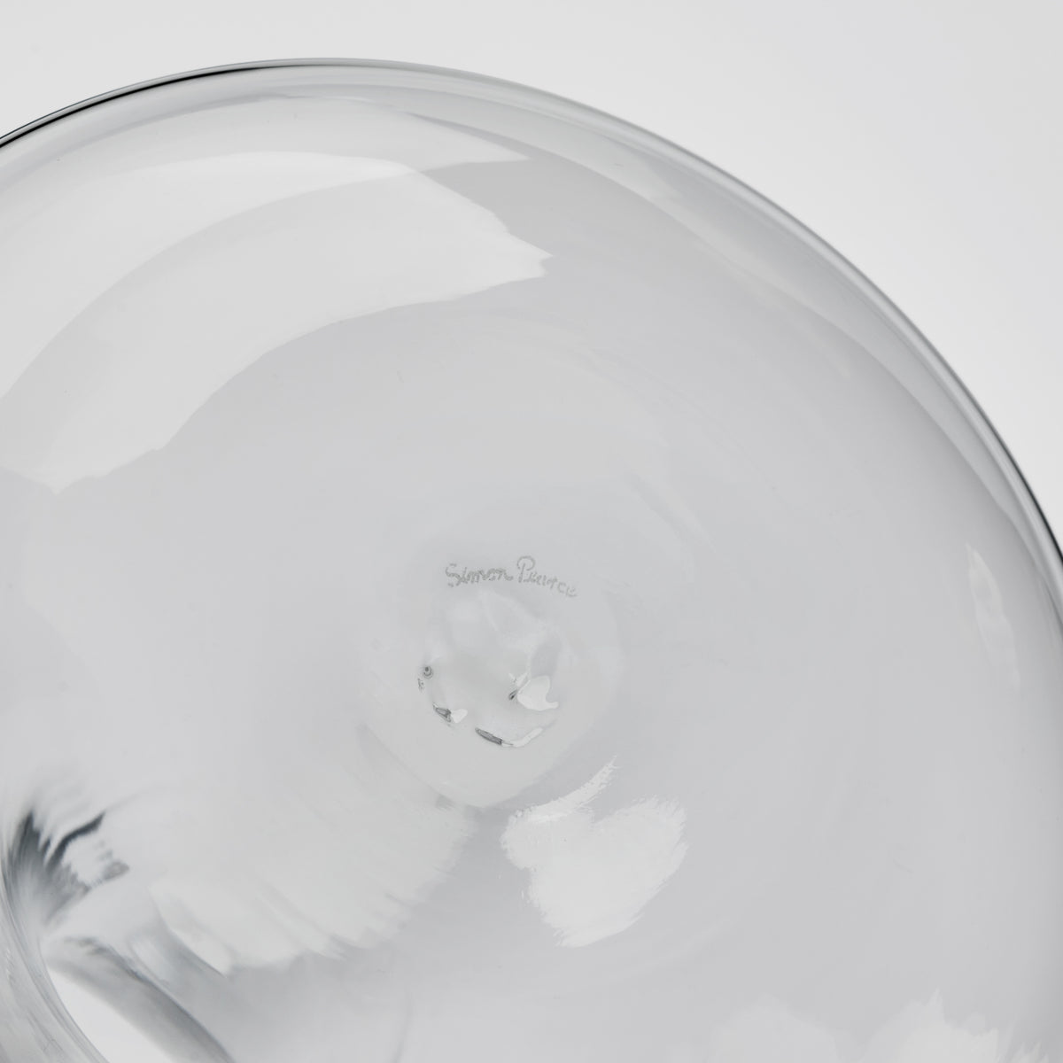 Clear glass wine decanter with curved body and artist signature etched on interior base.