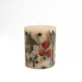 Cream pillar candle with embedded dried flowers and leaves in red, orange, green, and brown tones.