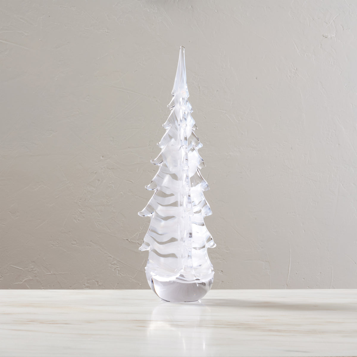 Clear acrylic evergreen tree with layered branches and pointed top on white base.