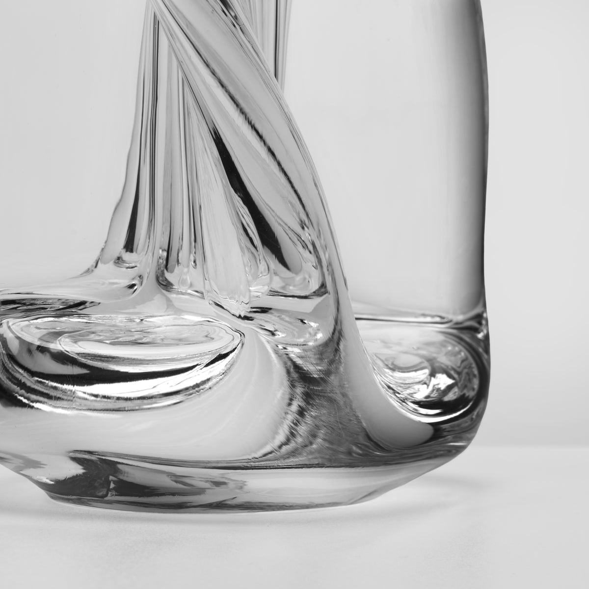Clear glass sculpture with spiraling four-sided form and smooth base detail.