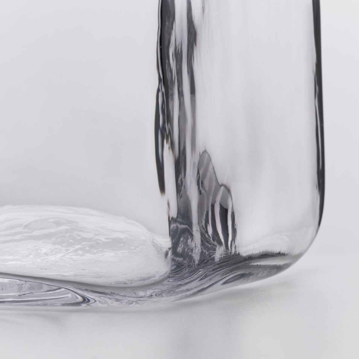 Clear glass decanter with curved form and organic swirl pattern detail at base.