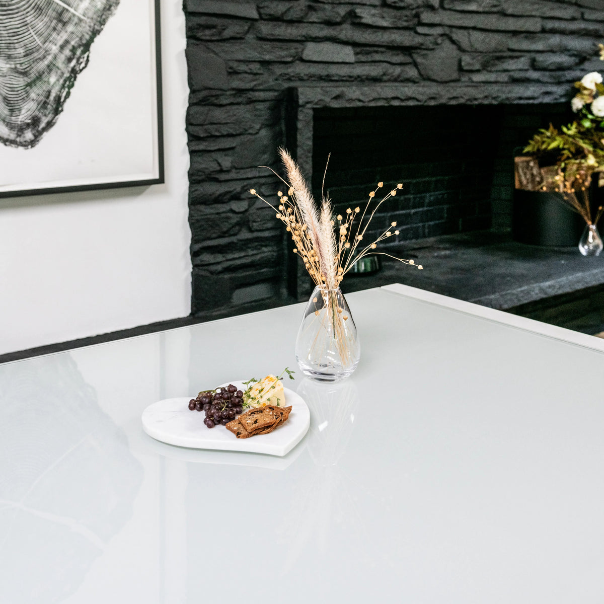 White marble heart-shaped serving board with grapes and crackers displayed on a table.