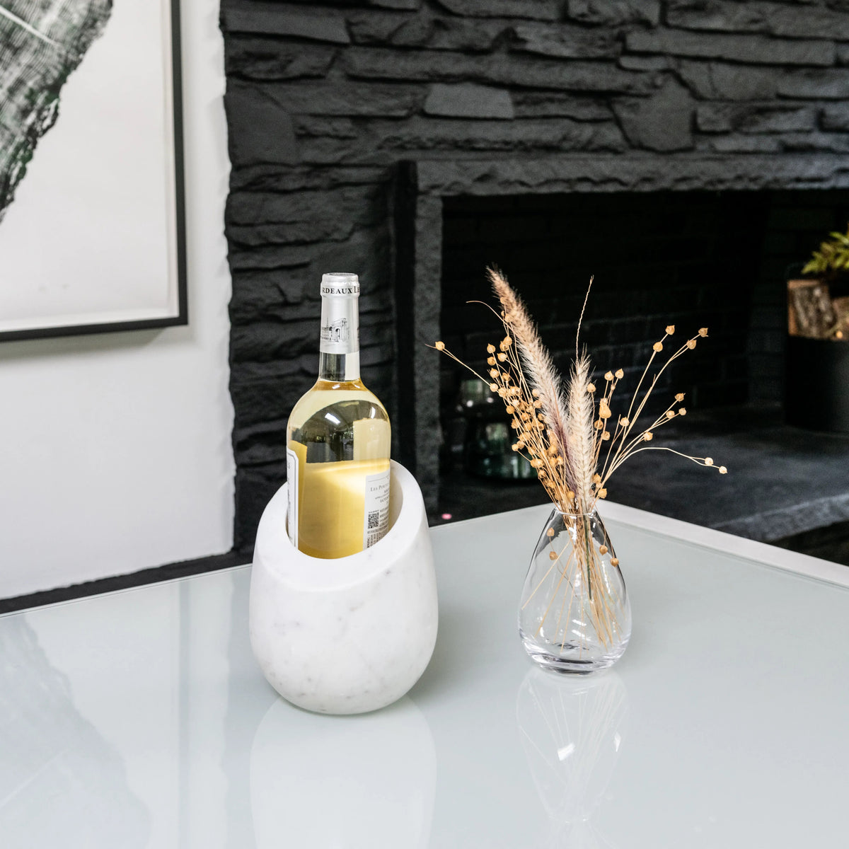 White marble wine chiller holding a bottle of white wine on a table.