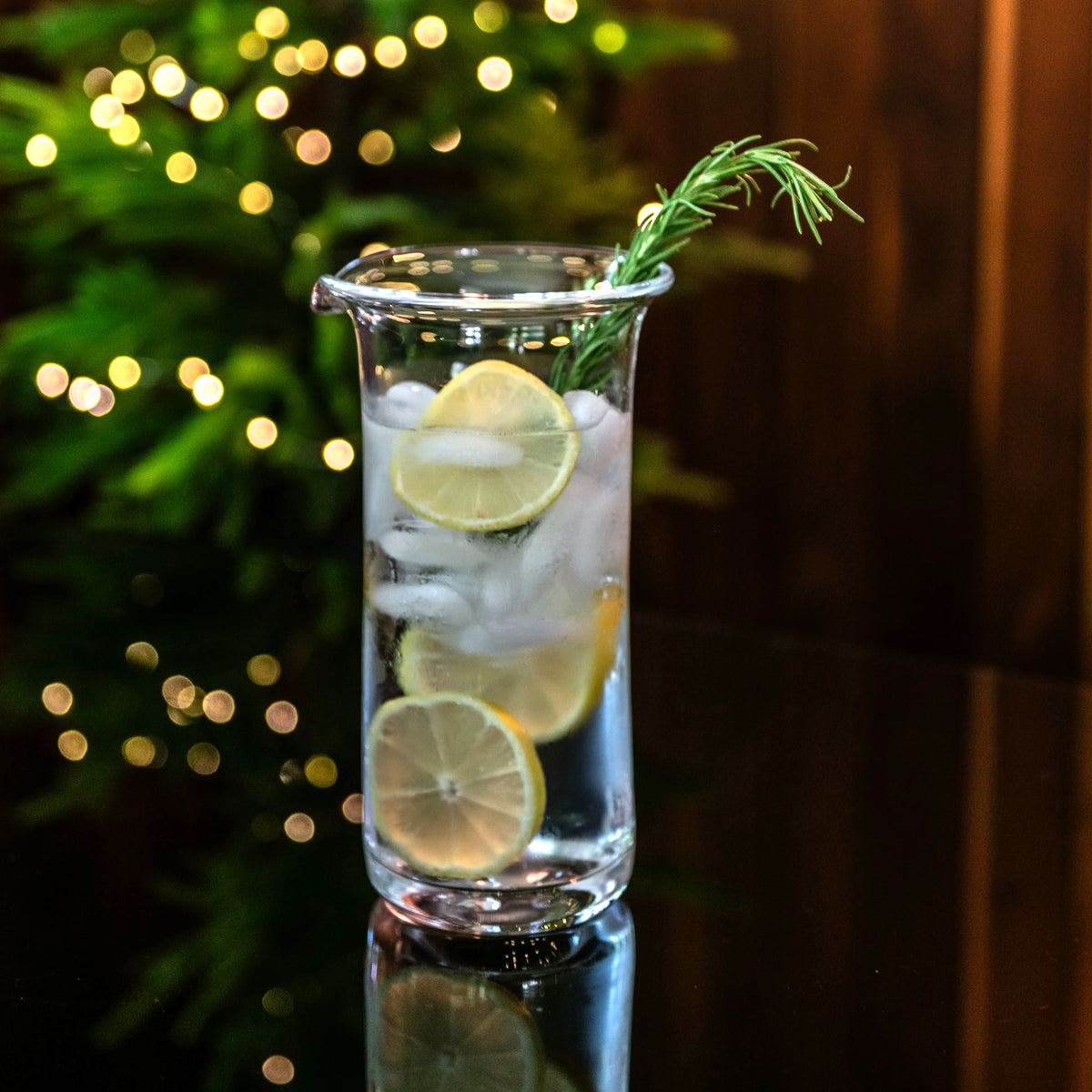Tall glass pitcher filled with ice, lemon slices, and fresh rosemary sprig.