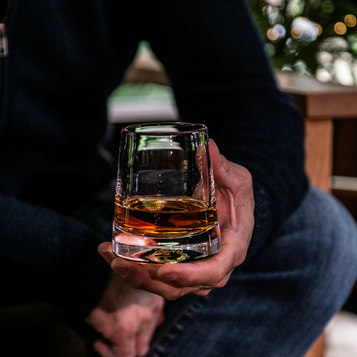 Person holding a rocks glass filled with amber bourbon whiskey.