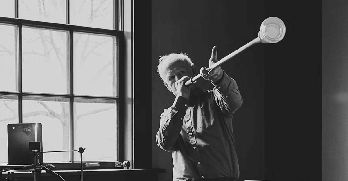 Simon Pearce blowing molten glass on a blowpipe in his Vermont workshop