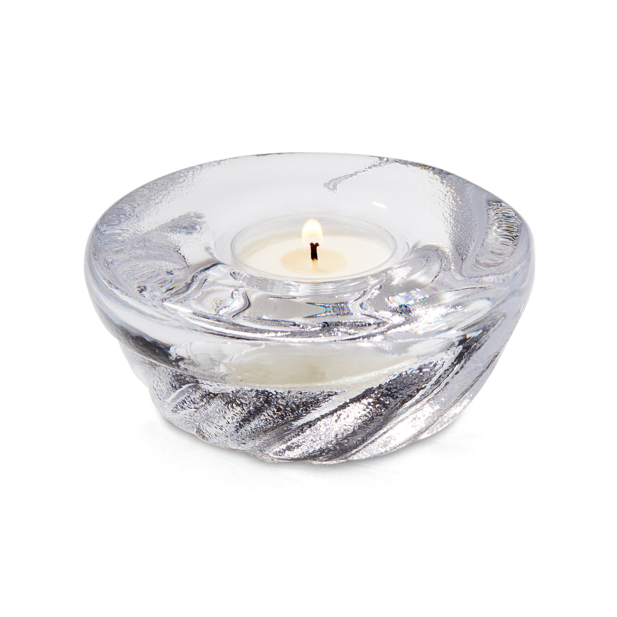 Clear glass shell-shaped tealight holder with lit cream candle inside.