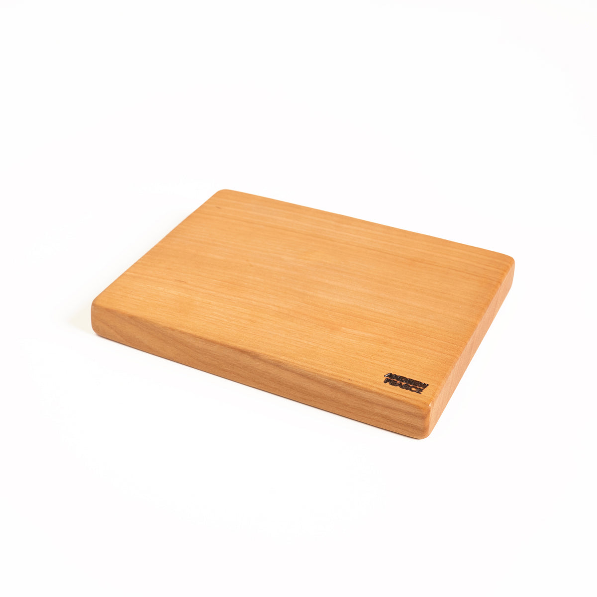 Light wood cutting board with square edges and rounded corners, small manufacturer label on lower right.