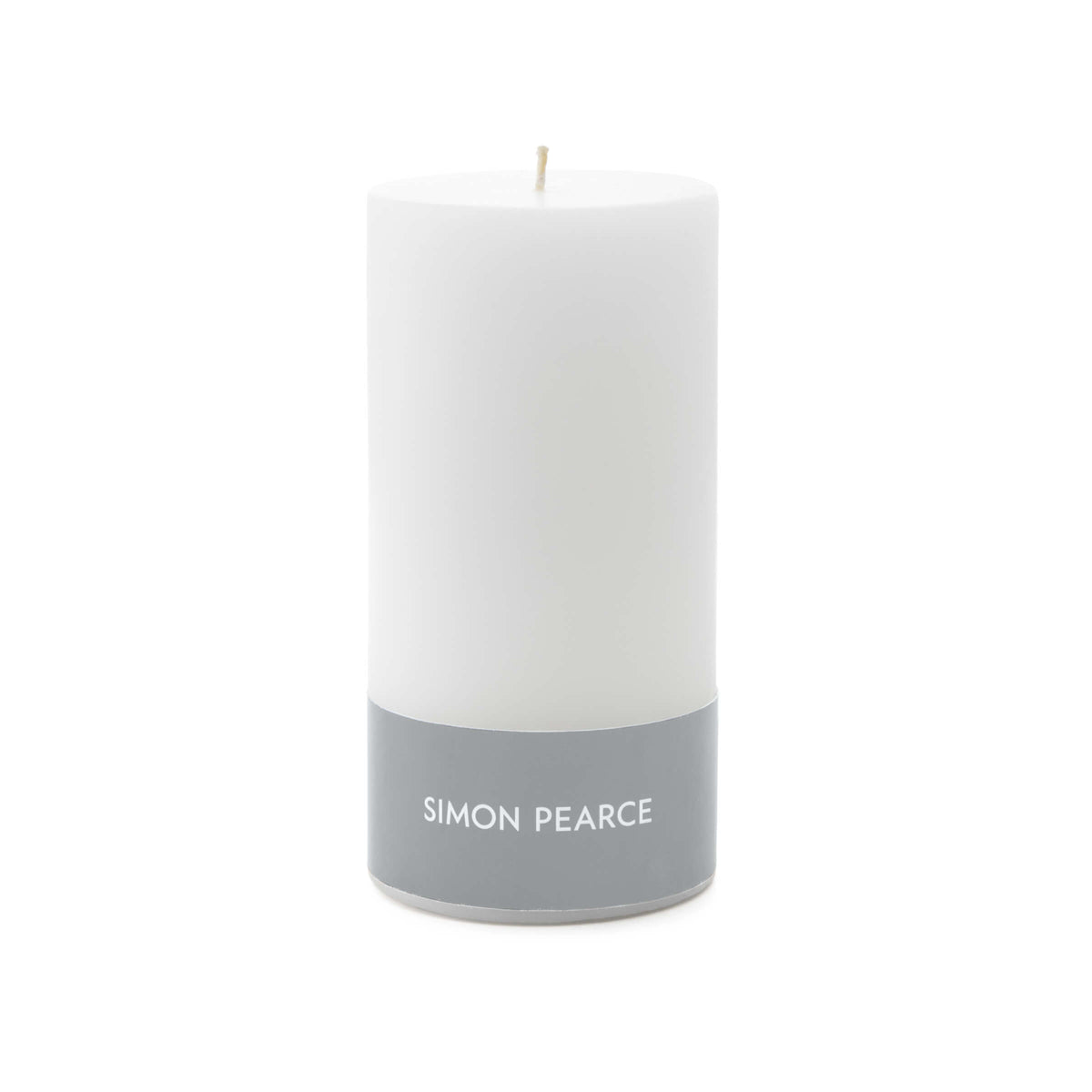 White cylindrical pillar candle with cream wick and gray band labeled "SIMON PEARCE" at base.